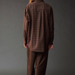 Back view of the Mijeong Park brown plaid shirt showing its oversized silhouette and curved hem