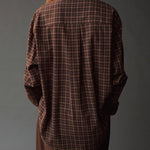 Close back view of the Mijeong Park Oversized Plaid Shirt showing the center pleat and curved hem