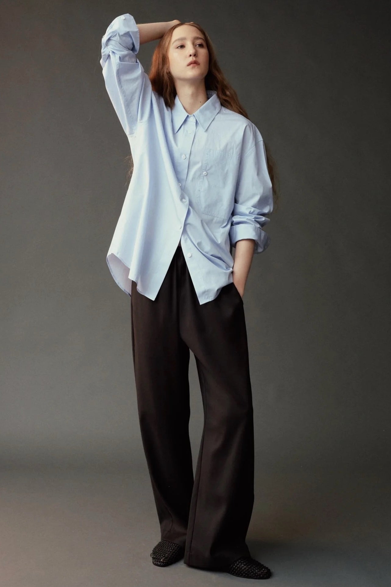 Model wearing the Mijeong Park Oversized Shirt in light blue with relaxed dark trousers