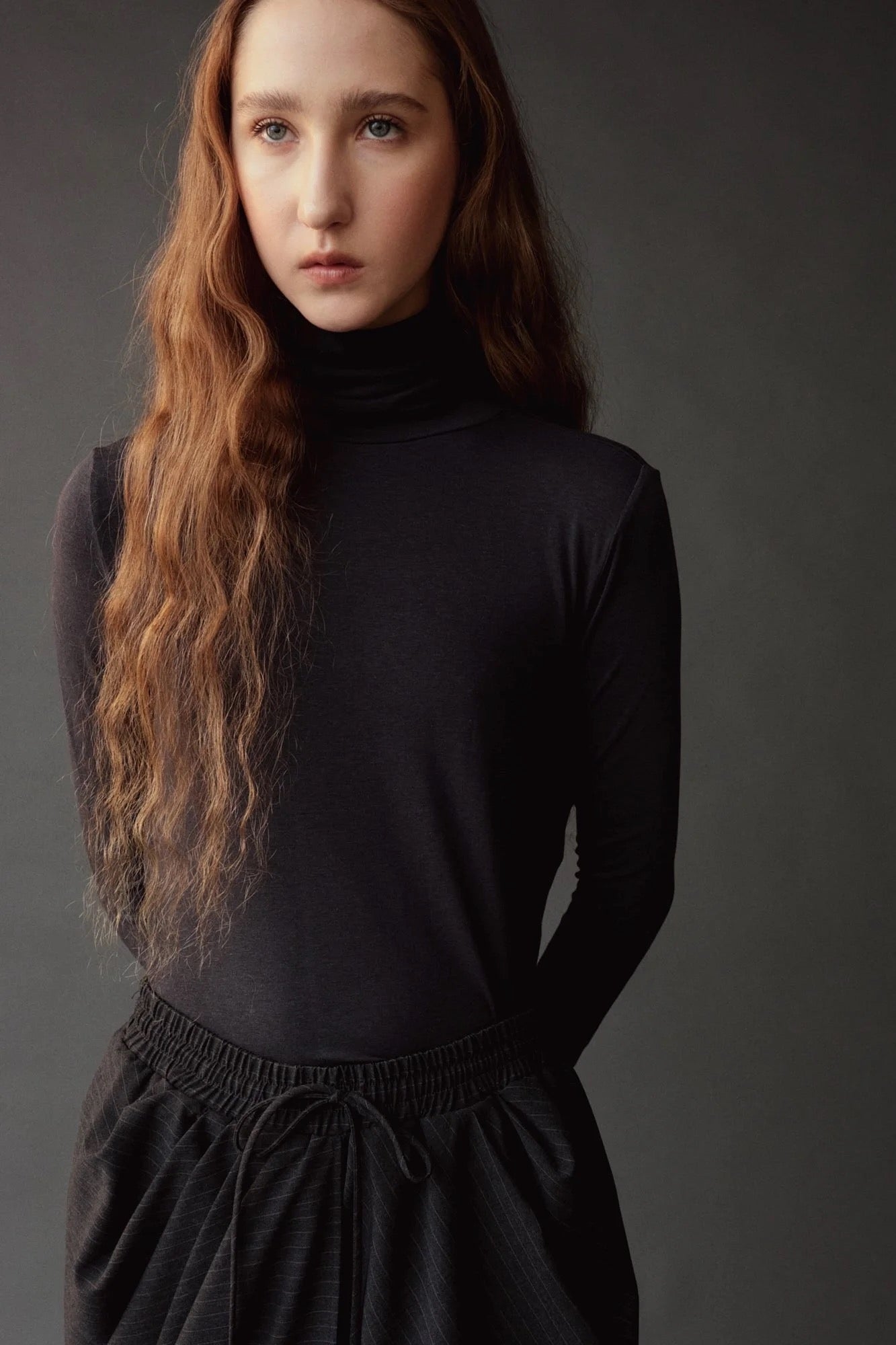 Close up of the graphite roll neck jersey top showing its softly gathered neckline.