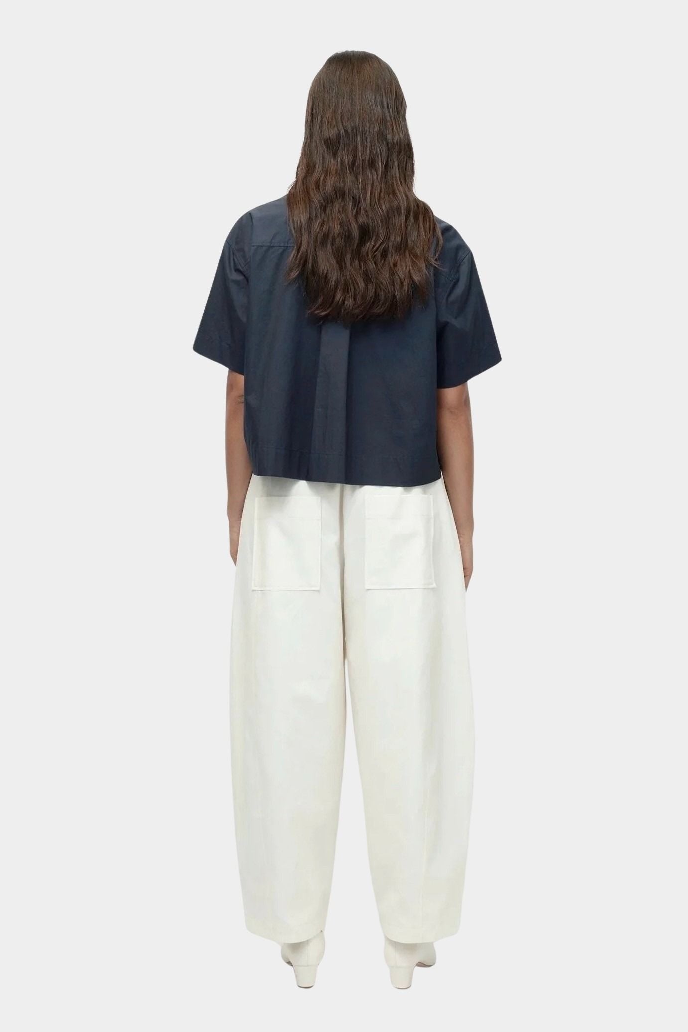Back view of cropped navy cotton poplin short sleeve shirt with boxy silhouette