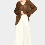Full outfit view of white wide leg pants styled with oversized brown sweater and sandals