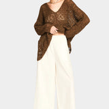 Full outfit view of white wide leg pants styled with oversized brown sweater and sandals