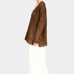Side view of white wide leg pants styled with brown knit top, relaxed fit and ankle length silhouette