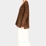 Side view of white wide leg pants styled with brown knit top, relaxed fit and ankle length silhouette