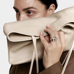 Modern Weaving Narrow Oval Tote Taupe worn on shoulder showing slim vertical profile and refined shape