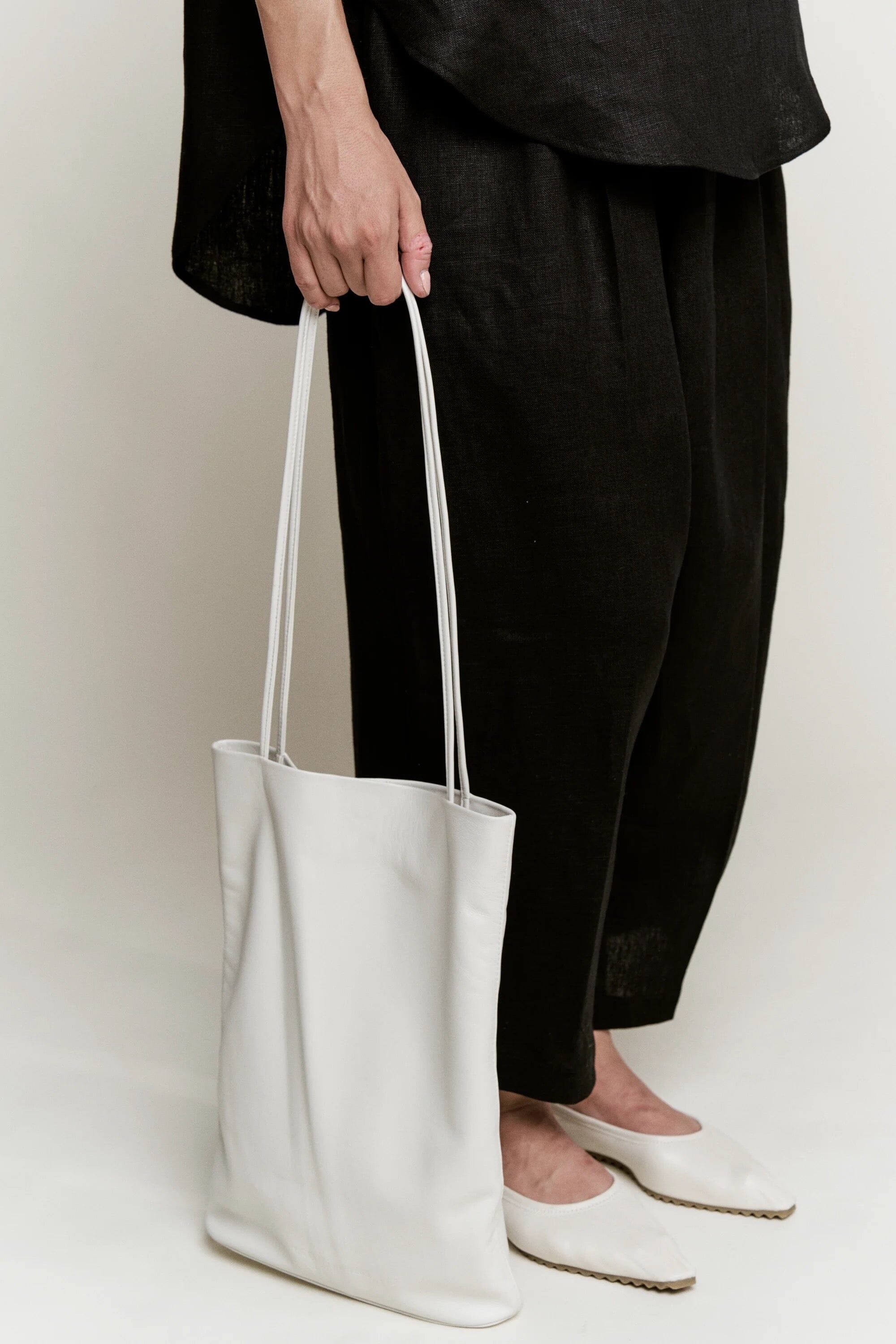 Modern Weaving Slim Elongated Tote Creme worn as shoulder bag with tall vertical silhouette and slim straps