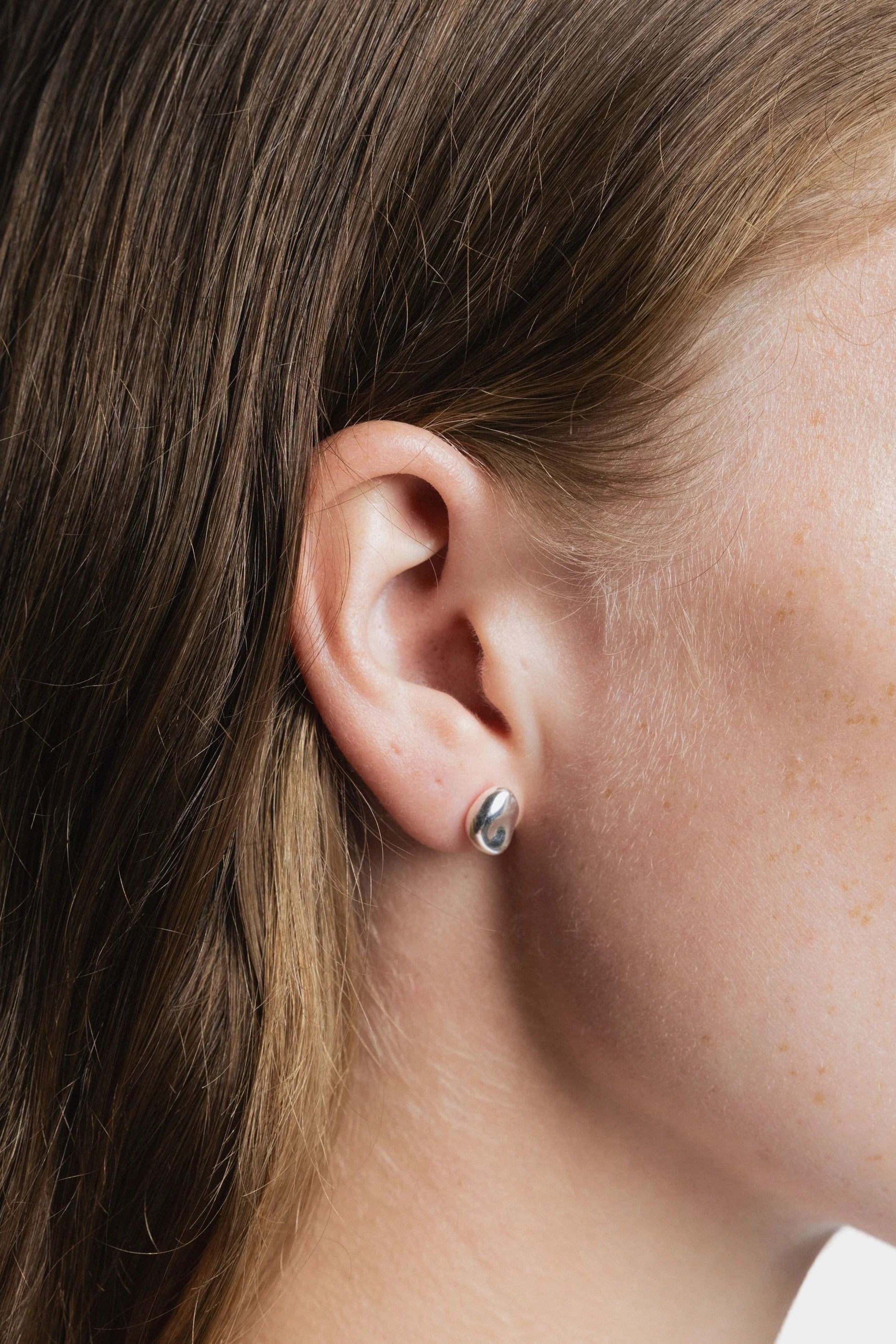 Bean Stud Earrings Sterling Silver Wolf Circus worn close up on ear polished silver stud earrings